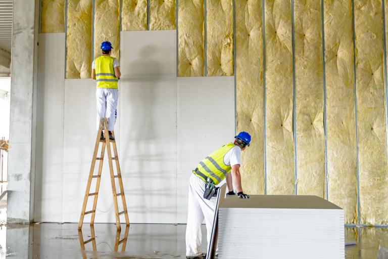 Tradesmen hanging drywall on a construction site